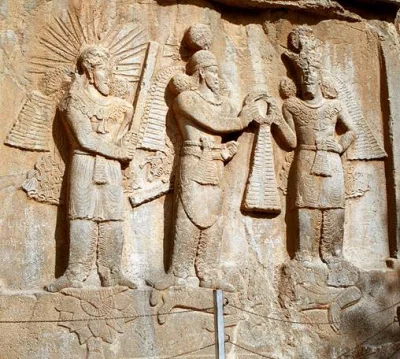 Бог Митра (Мифра, Михр), А(х)ура Мазда и царь Шапур II Сасанид над телом побежденного Шапуром римского императора Юлиана II Отступника. Накш-э Ростам.