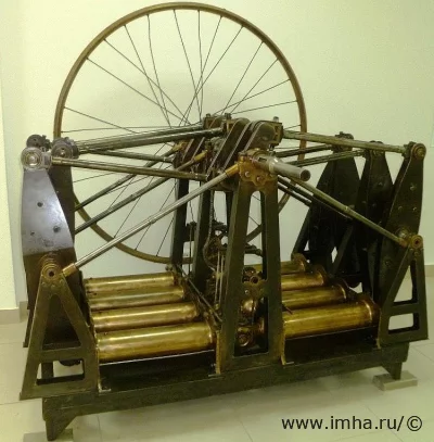 Мотор Костовича. 1883 г. С подставкой. 1883 г. Железо, бронза, сталь, заводское производство, длина - 1910 мм, ширина - 1700 мм, высота - 1870 мм. "Центральный музей Военно-воздушных сил" филиал ФГБУКиИ "Центральный музей Вооруженных Сил Российской Федерации" МО РФ.  Двигатель восьмицилиндровый, оппозитивный, с горизонтальным расположением цилиндров, соединённых в две группы по четыре цилиндра. Для равномерности хода двигателя применён маховик большого размера.