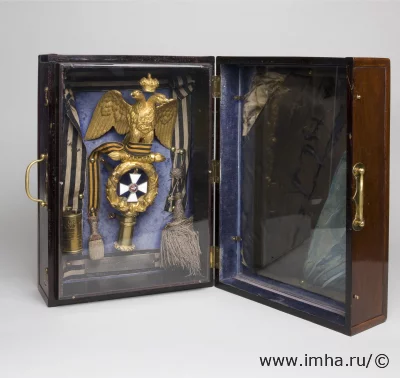 Знамя и знаменные принадлежности первого батальона лейб-гвардии Гренадерского полка образца 1813 года, пожалованного 1-му батальону 30 марта 1856 года. Навершие образца 1875 года. Россия, XIX в. Знамя: шелк, галун, латунь, позолота, эмаль; футляр: красное дерево, латунь, органическое стекло, 42,0х29,5х20,0 см. ГЭ