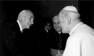 Ганс Урс фон Бальтазар приветствует Папу Иоанна Павла II, на заднем фоне кардинал Йозеф Ратцингер (будущий папа Бенедикт XVI).